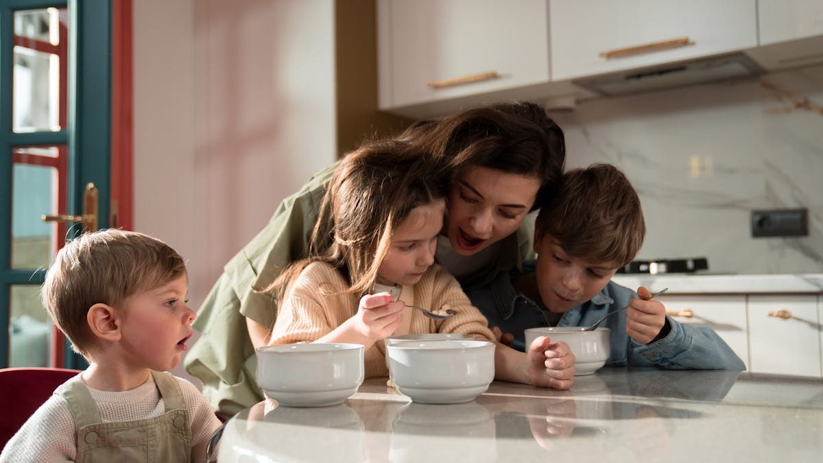 Mother and children enjoying a cozy breakfast together in a modern kitchen setting.